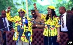 FILE - Zimbabwe's President Robert Mugabe, left, and his wife Grace chant the party's slogan during a solidarity rally in Harare, Wednesday, Nov. 8, 2017.
