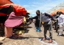 Seorang perempuan Somalia menjual buah-buahan kepada pelanggan yang berdiri di papan tanda jarak sosial, sebagai langkah untuk membendung penyebaran wabah Covid-19, di pusat pasar di distrik Hamarweyne di Mogadishu, Somalia 16 April 2020. (Foto: Reuters)