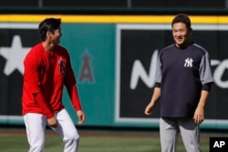 Los Angeles Angels starting pitcher Shohei Ohtani, left, and New York Yankees starting pitcher Masahiro Tanaka, both of Japan, share a light moment on the field before a baseball game Friday, April 27, 2018, in Anaheim, Calif. (AP Photo/Jae C. Hong)