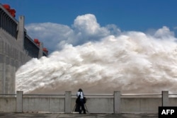 This picture taken on September 3, 2014 shows a man taking pictures of floodwater released from the Three Gorges Dam, a gigantic hydropower project on the Yangtze river, in Yichang, central China's Hubei province, after heavy downpours in the upper reaches of the dam caused the highest flood peak of the year.