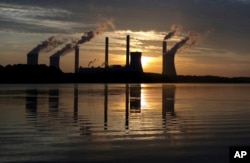 In this June, 3, 2017, file photo, the sun sets behind Georgia Power's coal-fired Plant Scherer, one of the nation's top carbon dioxide emitters, in Juliette, Ga. (AP Photo/Branden Camp, File)