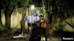 A Venezuelan man cuts the hair of his friend at a gym which has turned into a shelter for Venezuelans in Boa Vista, Brazil Nov. 17, 2017.