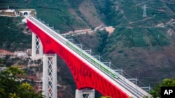 FILE - In this photo released by Xinhua News Agency, a train of the Laos-China Railway crosses a major bridge over the Yuanjiang River in southwestern China's Yunnan Province, Dec. 3, 2021.