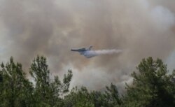 Sebuah pesawat pemadam kebakaran menjatuhkan air saat memadamkan kebakaran hutan di dekat Marmaris, Turki, 30 Juli 2021. (Foto: REUTERS/Kenan Gurbuz)