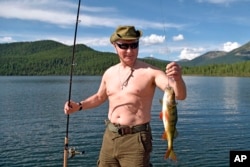 FILE - Russian President Vladimir Putin holds a fish he caught during a mini-break in the Siberian Tyva region, in this photo released by Kremlin press service on Aug. 5, 2017.