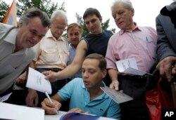 FILE - Vladimir Milov, a leader of the Democratic Choice party, signs autographs during a rally of party's supporters in Moscow, June 25, 2011.