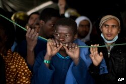 FILE - Sub-Saharan migrants wait their turn to leave the Golfo Azzurro rescue vessel after arriving at the port of Pozzallo, south of Sicily, Italy, with more than 220 migrants aboard, rescued by members of Proactive Open Arms NGO, Feb. 5, 2017.