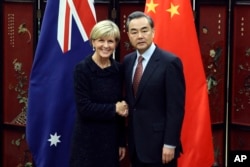 Australian Foreign Minister Julie Bishop, left, and Chinese Foreign Minister Wang Yi pose for photographers as she arrives for a meeting at the Ministry of Foreign Affairs in Beijing, Wednesday, Feb. 17, 2016.