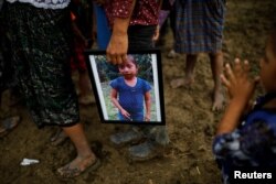 A man holds a picture of Jakelin Caal, 7, during her funeral at her home village of San Antonio Secortez, in Guatemala, Dec. 25, 2018.