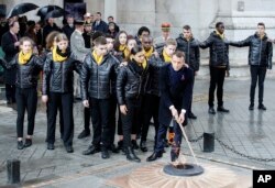 French President Emmanuel Macron lights up with children the Tomb of the Unknown Soldier under the Arc de Triomphe during ceremonies, Nov. 11, 2018 in Paris.