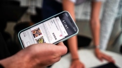 Co-founder of the app Stint, Sol Schlagman, holds his phone showing the app running, at their headquarters in Camden, London, Monday, Aug. 23, 2021. The app is becoming an important part of reducing the labor shortage in the U.K. Critics say apps like this that find temporary employees could reduce benefits given to permanent employees like sick time. (AP Photo/Alberto Pezzali)