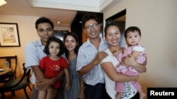 Reuters reporter Wa Lone poses with wife Pan Ei Mon and daughter, along with Reuters reporter Kyaw Soe Oo carrying his daughter next to wife Chit Su Win, after being freed from prison, after receiving a presidential pardon in Yangon, Myanmar, May 7, 2019.