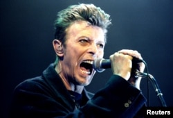 FILE - British Pop Star David Bowie screams into the microphone as he performs on stage during his concert in Vienna, Feb. 4, 1996.
