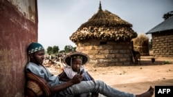 Le berger des Fulani, âgé de 30 ans, Isa Ibrahim utilise son téléphone tout en jouant avec son fils Suleima Isa, âgé de 4 ans, devant son domicile dans la réserve de Kachia Grazing, État de Kaduna, au Nigeria, le 16 avril 2019.