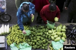 FILE - People select vegetables at a open-air morning market in Shenyang, Liaoning province, April 10, 2015.