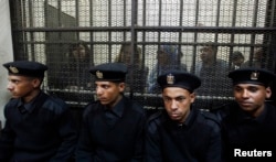 FILE - Some of the 14 Egyptian activists who were accused of working for unlicensed nongovernmental organizations (NGOs) and receiving illegal foreign funds stand in a cage during the opening of their trial in Cairo, Feb. 26, 2012.