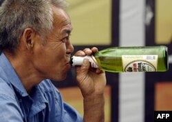Seorang pekerja bangunan minum bir saat istirahat kerja di Beijing, China, 30 Juli 2004.