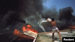 រូបឯកសារ៖ បុរស​ម្នាក់​ព្យាយាម​ជះ​ទឹក​ពន្លត់​ភ្លើង ដើម្បី​កុំ​ឲ្យ​ភ្លើង​ឆេះ​ដល់​ផ្ទះ​របស់​ខ្លួនកាលពីថ្ងៃទី៣ ខែមិនា ឆ្នាំ២០០៣។