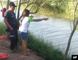 In this Sunday, June 23, 2019 photo, Tania Vanessa Ávalos of El Salvador speaks with Mexican authorities after her husband and nearly two-year-old daughter were swept away by the current in Matamoros, Mexico, while trying to cross the Rio Grande.
