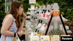 FILE - A customer tries a lipstick at a shop in central Seoul, South Korea, Aug. 6, 2013. Chinese sanctions against South Korea include restricting the import of South Korean cosmetics.