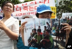 An unidentified North Korean defector holds a picture of nine North Korean defectors who were flown home as she cries during a rally protesting against Laos' repatriation of them, in Seoul, South Korea, June 5, 2013.