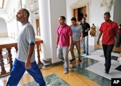 A security officer (R) escorts a group of unidentified, recently released political prisoners to a meeting with a truth commission at the Venezuelan Foreign Ministry, in Caracas, Venezuela, June 1, 2018.