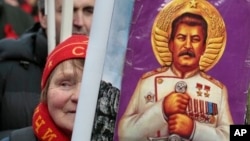 A woman holds a portrait of Soviet dictator Josef Stalin during a communist rally marking Defenders of the Fatherland Day, Moscow, Feb. 23, 2013.