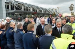 The Belgian Prime Minister Charles Michel, center, shakes hands with police officers and first responders in front of the damaged Zaventem Airport terminal in Brussels on March 23, 2016.
