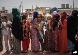 FILE - Women and children stand in line for food at Dibaga camp for internally displaced civilians in Iraq, Aug. 7, 2016.