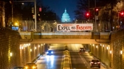 An activist with the group ShutDownDC takes a photo of a banner put up by the group calling on Congress to 'expel all fascists' on an overpass near the US Capitol in Washington on Jan. 5, 2022.