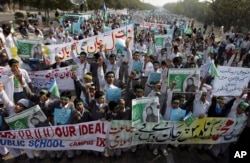FILE - Students chant slogans while holding banners and posters showing Mumtaz Qadri, the killer of Punjab Governor Salman Taseer, during a rally to protest against any attempts to modify blasphemy laws, in Karachi, Pakistan, Jan. 20, 2011. Qadri was eventually executed in prison.