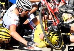 Britain's Chris Froome, wearing the overall leader's yellow jersey, right, Netherlands’ Bauke Mollema, center, and Australia’s Richie Porte crash at the end of the twelfth stage of the Tour de France cycling race.
