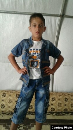 Khaled poses for a picture taken by his mother in their tent inside a refugee camp for orphans, in Idlib's countryside.