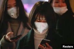 Women wearing face masks wait for the bus on an extremely polluted day with red alert issued, in Langfang, Hebei province, China, Dec. 19, 2016.