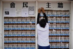 FILE - A student union member removes adjusts posters to make space for other students to display notices at the Chinese University of Hong Kong in Hong Kong, September 7, 2017.
