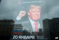 The U.S. Embassy building is reflected in a window of a Russian military outerwear shop "Armia Rossii" (Russian Army) displaying a poster of U.S. President Donald Trump, in downtown Moscow, Russia, Jan. 20, 2017. The poster offered a discount for embassy employees and U.S. citizens on Trump's Inauguration Day.