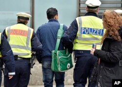Police lead away a man at the main train station, Jan. 12, 2016, in Cologne, Germany. New Year’s Eve sexual assaults and robberies in Cologne were blamed largely on foreigners and pushed the discussion about the migration crisis.