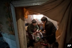 FILE - An elderly woman casts her ballot at home during the presidential election in Mariinka, near a contact line not far from Donetsk, eastern Ukraine, March 31, 2019.
