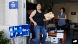 Cynthia Ameli, center, a Chinese-American, picks up materials from Sarah Gibson before heading out to canvass for presidential candidate Hillary Clinton in Las Vegas, Feb. 12, 2016.