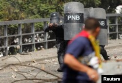 A police officer fires rubber bullets at demonstrators during a protest against Venezuelan President Nicolas Maduro's government, in Caracas, Venezuela Jan. 23, 2019.