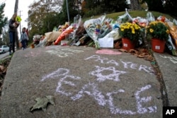 A mother and her child arrive to place flowers at a spontaneous memorial of flowers and sidewalk writing a block from the Tree of Life Synagogue, Oct. 29, 2018.