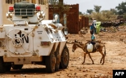 A Sudanese boy rides a donkey past a UN-African Union mission in Darfur (UNAMID) armoured vehicle in the war-torn town of Golo in the thickly forested mountainous area of Jebel Marra in central Darfur.
