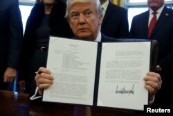 FILE - U.S. President Donald Trump signs a memorandum to security services directing them to defeat the Islamic State in the Oval Office at the White House in Washington, Jan. 28, 2017.