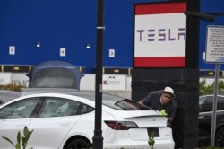 Seorang karyawan Tesla membersihkan sebuah mobil di showroom Tesla di Burbank, California, 24 Maret 2020. (Foto: AFP)