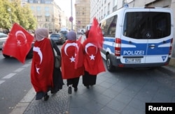 Supporters of Turkish President Recep Tayyip Erdogan walk along the security zone around the Adlon Hotel in Berlin, Sept. 27, 2018.