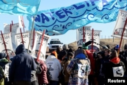 Protesters lock arms during a standoff with a police car along the pipeline route during a protest against the Dakota Access pipeline near the Standing Rock Sioux Reservation in St. Anthony, N.D., Nov. 11, 2016.