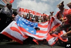 Filipino tribal groups and activists shout slogans as they burn a mock U.S. flag near the Malacanang presidential palace in Manila, Philippines, Oct. 21, 2016.