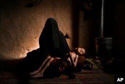 Žena drži svoju četverogodišnju kćer Naziju, koja pati od akutne pothranjenosti, u njihovoj kući u blizini Herata, zapadni Afganistan, 16. decembra 2021.