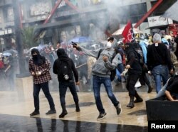 Demonstrators throw stones in clashes with riot police that occurred during the march in Mexico City, Sept. 26, 2015.