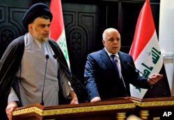 FILE - In this photo provided by the Iraqi government, Iraqi Prime Minister Haider al-Abadi, right, and Shi'ite cleric Muqtada al-Sadr hold a press conference in Baghdad, May 20, 2018.